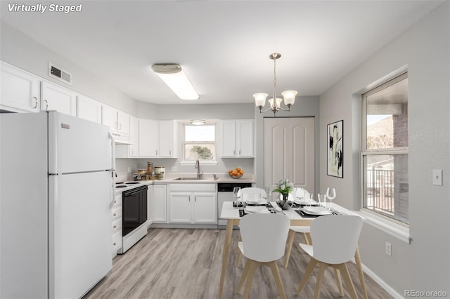 kitchen with a wealth of natural light, white cabinetry, sink, hanging light fixtures, and white appliances