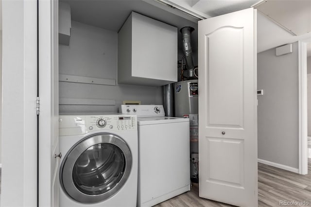 clothes washing area featuring cabinets, gas water heater, light hardwood / wood-style flooring, and washer and clothes dryer