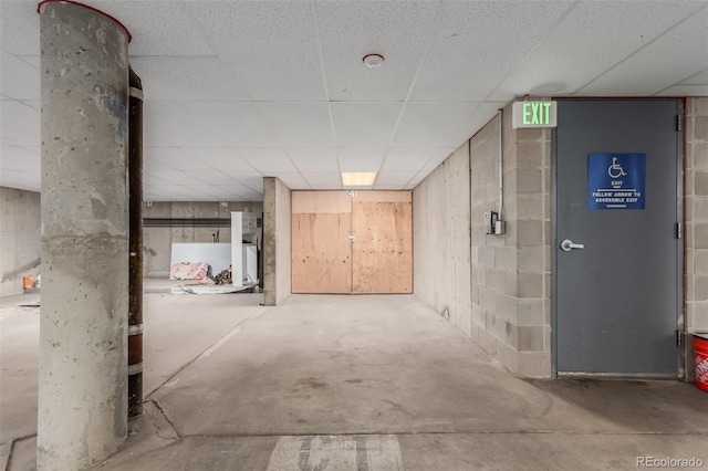 hall with a paneled ceiling and concrete floors