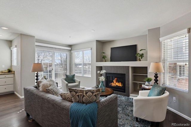 living area with baseboards, dark wood-type flooring, and a tile fireplace