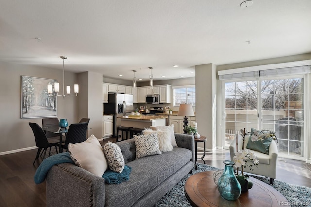 living room with recessed lighting, an inviting chandelier, baseboards, and wood finished floors