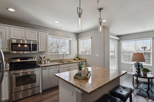 kitchen featuring a center island, appliances with stainless steel finishes, white cabinets, a sink, and a kitchen breakfast bar