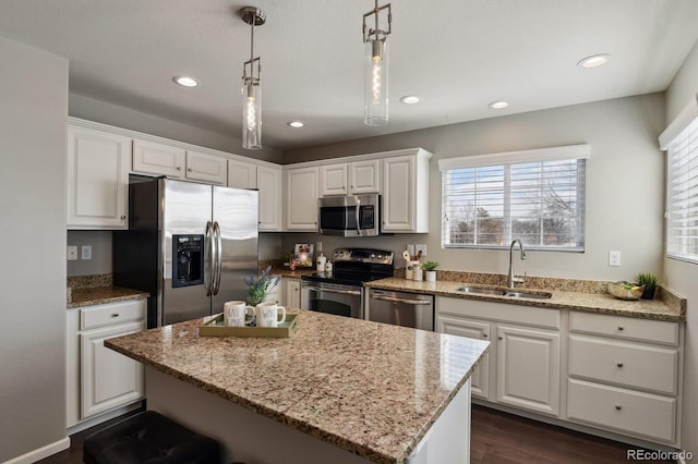 kitchen featuring light stone counters, appliances with stainless steel finishes, a sink, and white cabinetry