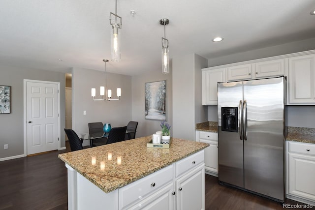 kitchen with light stone counters, a center island, dark wood finished floors, and stainless steel refrigerator with ice dispenser