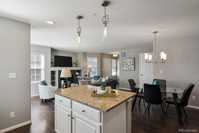 kitchen featuring a center island, pendant lighting, dark wood-style flooring, visible vents, and white cabinets