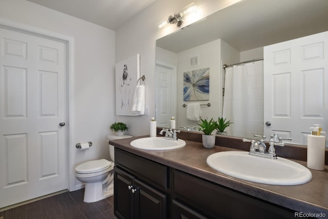 bathroom with toilet, double vanity, visible vents, and a sink