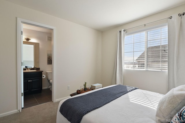 carpeted bedroom featuring connected bathroom, baseboards, and a sink