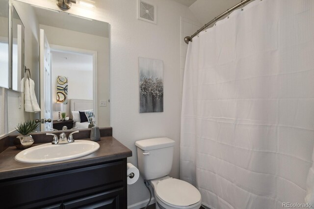 bathroom with visible vents, connected bathroom, vanity, and toilet