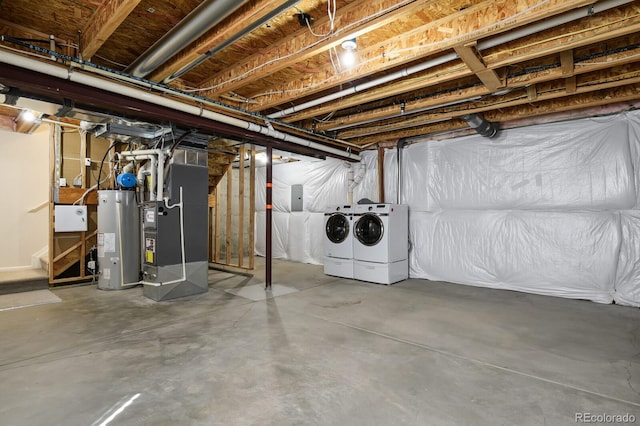 unfinished basement featuring washer and dryer, gas water heater, and heating unit