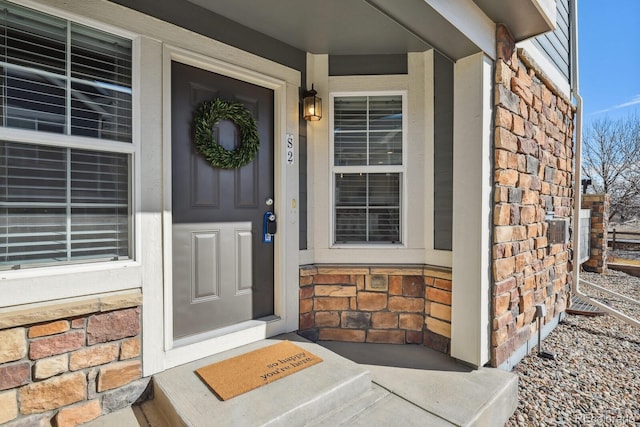 view of exterior entry featuring stone siding and brick siding