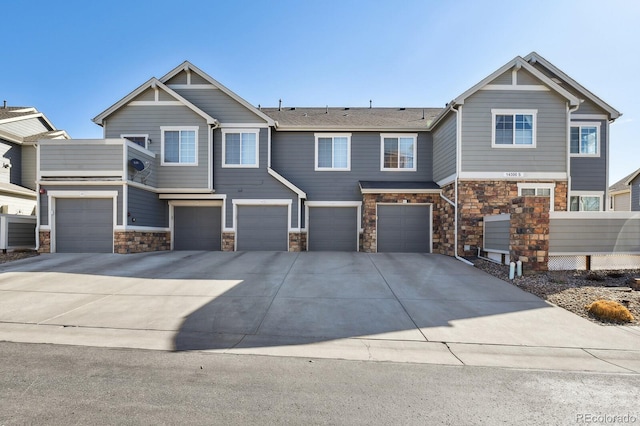 view of front facade featuring driveway, stone siding, and a garage