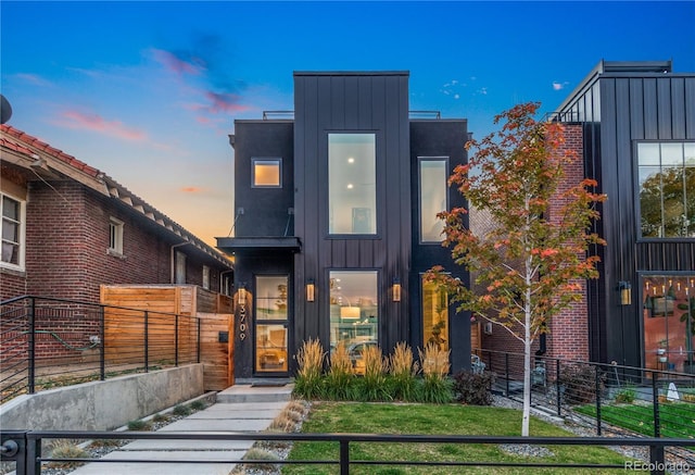 modern home featuring board and batten siding and fence