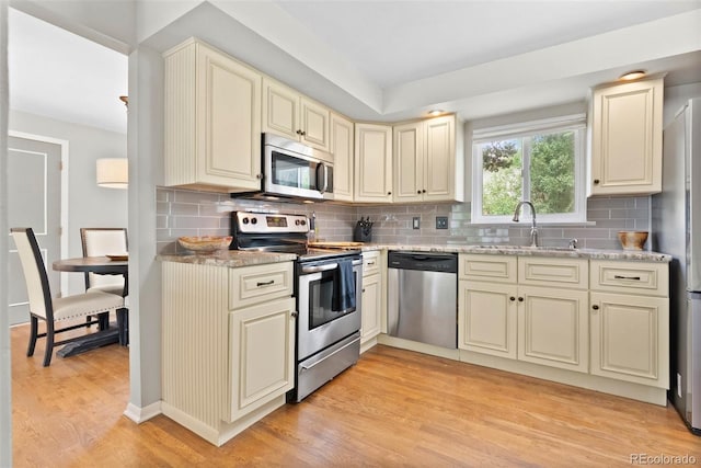 7306 S Dexter St, Centennial, CO 80122 - kitchen with stainless steel appliances, cream cabinets, light wood-style flooring, tasteful backsplash, and light stone countertops