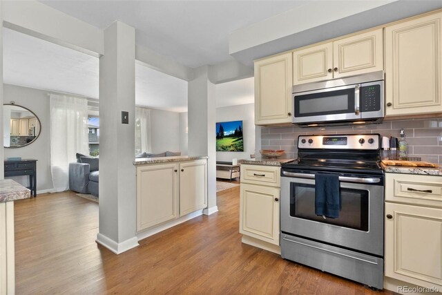 7306 S Dexter St, Centennial, CO 80122 - kitchen featuring stainless steel appliances, cream cabinets, light wood-style floors, and tasteful backsplash