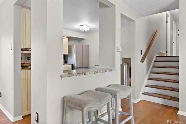 7306 S Dexter St, Centennial, CO 80122 - kitchen featuring freestanding refrigerator, light wood-style floors, a breakfast bar area, and light stone counters
