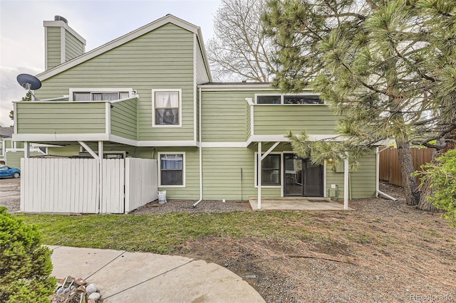 rear view of property featuring a chimney, fence, and a patio