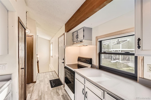 kitchen featuring electric range, under cabinet range hood, a textured ceiling, light wood-style flooring, and light countertops