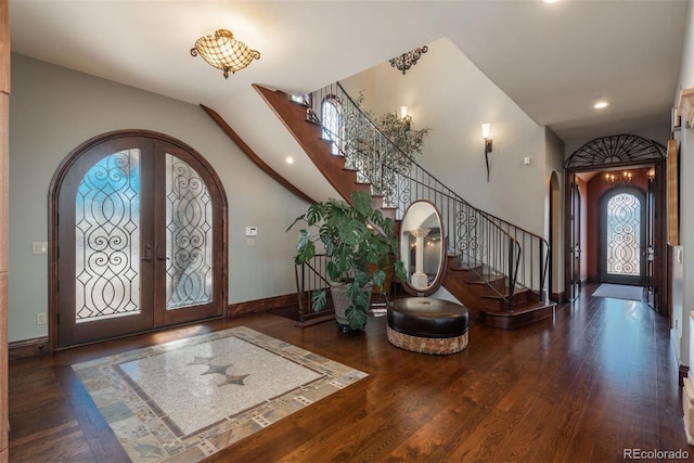 foyer with stairs, arched walkways, wood finished floors, and french doors