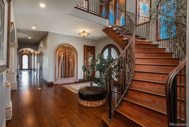 foyer featuring arched walkways, recessed lighting, wood finished floors, baseboards, and stairway