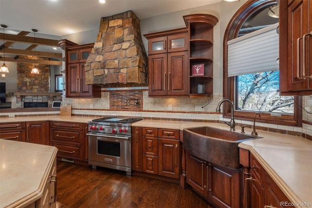 kitchen featuring light countertops, luxury stove, backsplash, and a sink