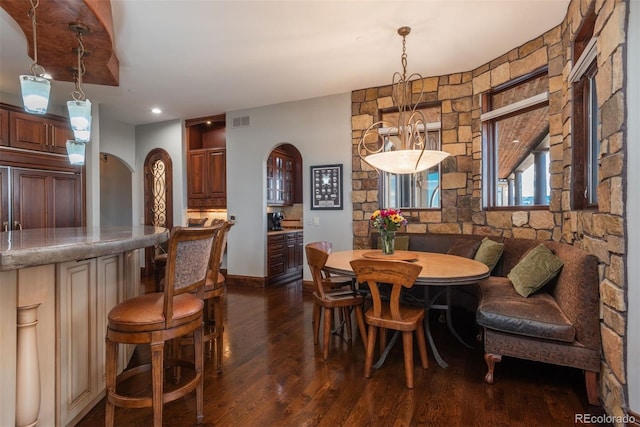 dining room with arched walkways, dark wood-style floors, and visible vents