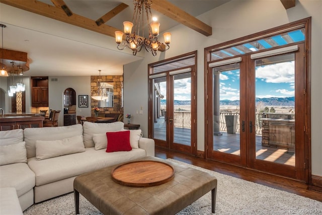 living area with arched walkways, a mountain view, wood finished floors, french doors, and beamed ceiling