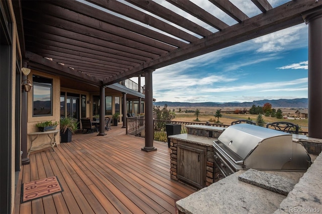 wooden deck with a mountain view, grilling area, a pergola, and area for grilling