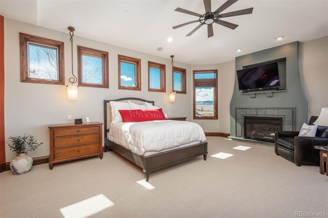 carpeted bedroom featuring a glass covered fireplace, baseboards, and recessed lighting