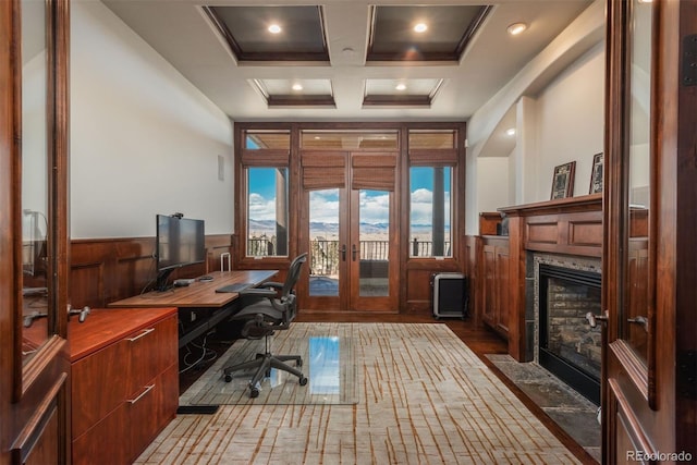 office space featuring a tile fireplace, coffered ceiling, wood finished floors, french doors, and wainscoting