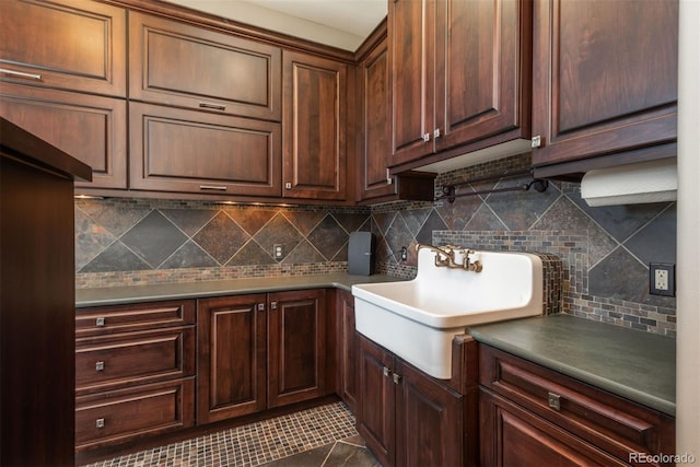 kitchen with dark tile patterned floors, backsplash, and a sink