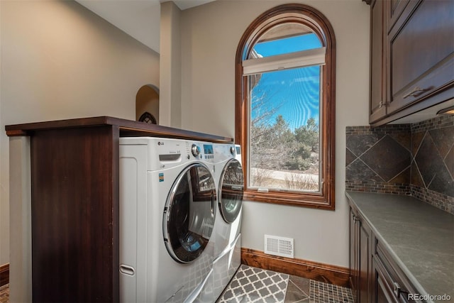 laundry area with cabinet space, plenty of natural light, visible vents, and washing machine and clothes dryer