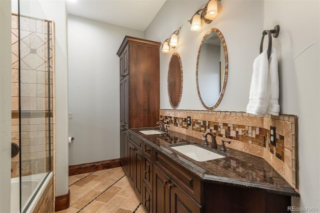 full bath with tiled shower / bath, backsplash, a sink, and baseboards