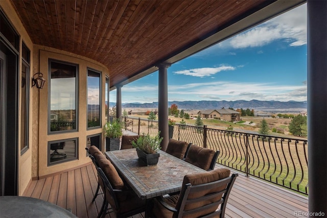 wooden deck with a mountain view and outdoor dining area