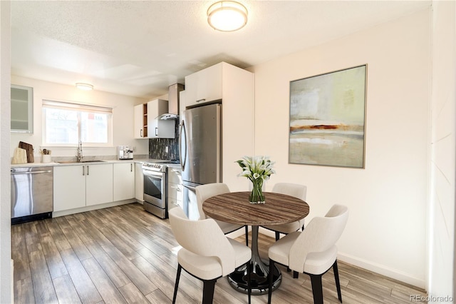 kitchen featuring light hardwood / wood-style floors, sink, white cabinetry, and stainless steel appliances