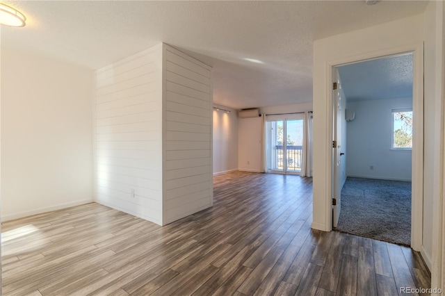 spare room with hardwood / wood-style flooring, a wall unit AC, and a healthy amount of sunlight