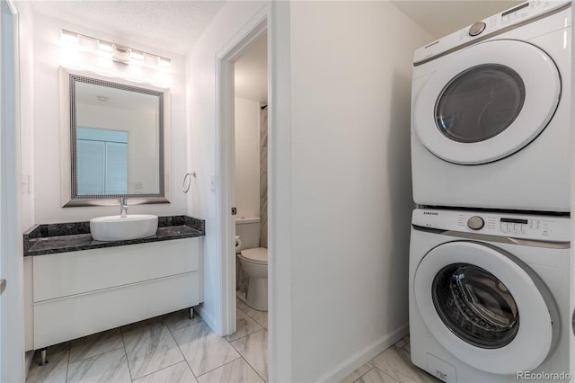 clothes washing area with a textured ceiling, stacked washer and dryer, and sink