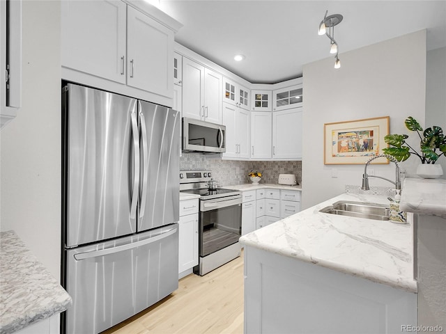 2716 W Greens Dr, Littleton, CO 80123 - kitchen with stainless steel appliances, a sink, backsplash, light wood-type flooring, and white cabinets