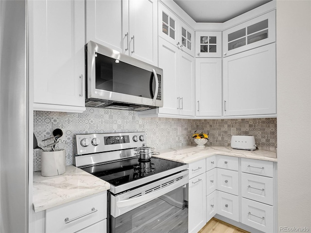 2716 W Greens Dr, Littleton, CO 80123 - kitchen with stainless steel appliances, white cabinets, light stone countertops, glass insert cabinets, and decorative backsplash