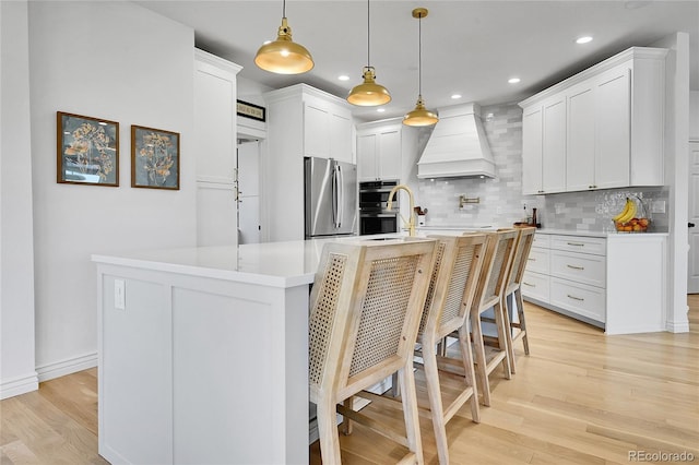 12408 W 83rd Ave, Arvada, CO 80005 - kitchen featuring premium range hood, stainless steel appliances, light countertops, light wood-style flooring, and tasteful backsplash