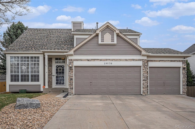 traditional home featuring a garage, concrete driveway, stone siding, a chimney, and a shingled roof
