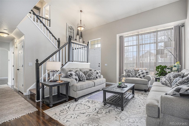living room with stairway, wood finished floors, arched walkways, and baseboards