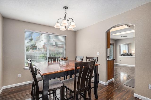 dining area with arched walkways, dark wood-type flooring, a chandelier, and baseboards