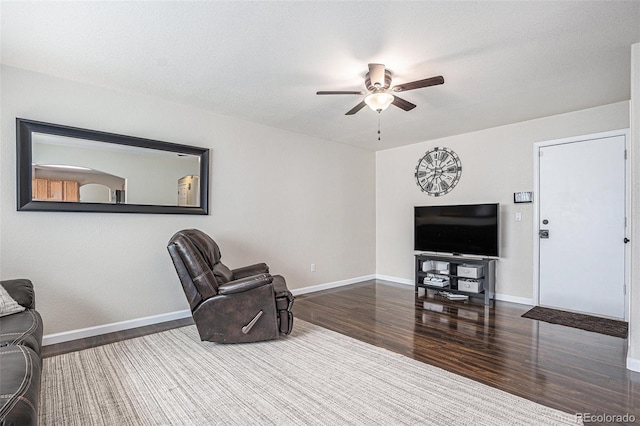 living area with ceiling fan, wood finished floors, and baseboards