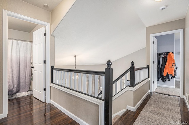 hallway featuring an upstairs landing, wood finished floors, and baseboards