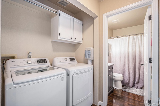 laundry area with washing machine and clothes dryer, dark wood-type flooring, and cabinet space