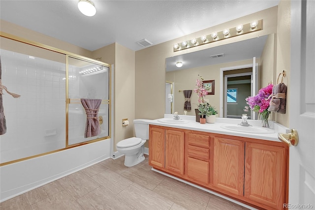 full bathroom with vanity, bath / shower combo with glass door, and toilet