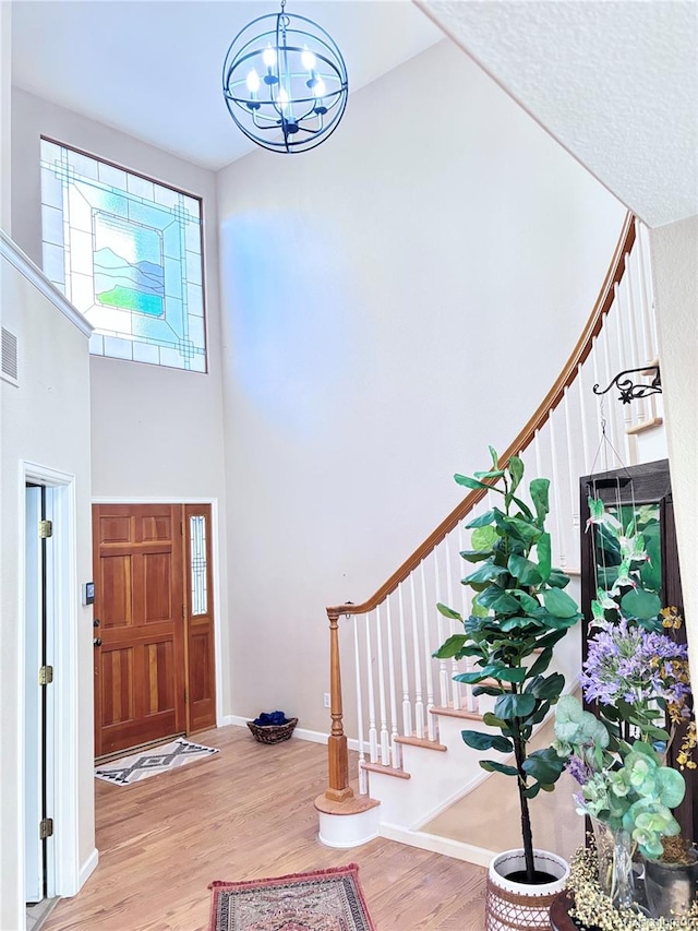 foyer with an inviting chandelier, hardwood / wood-style flooring, and a towering ceiling