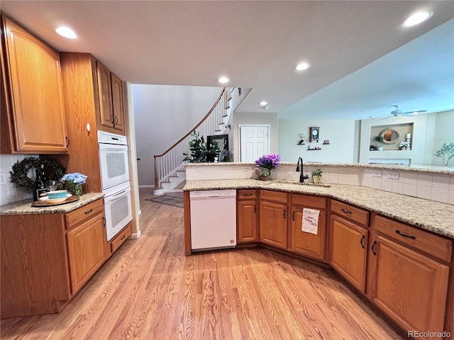 kitchen featuring white appliances, sink, light hardwood / wood-style flooring, and backsplash