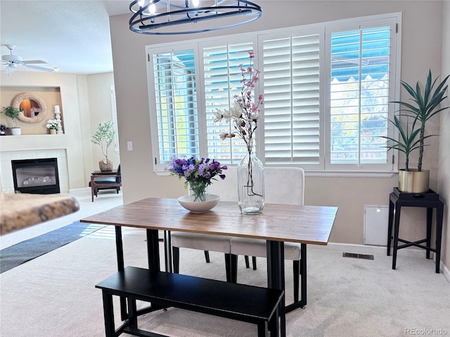 carpeted dining area with a tile fireplace and a chandelier