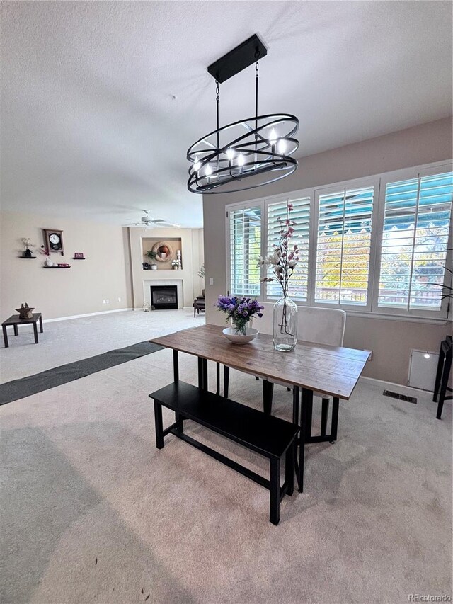 dining area with ceiling fan, light carpet, and a textured ceiling